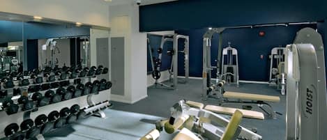 A gym with weightlifting equipment, mirrors, and a blue wall.
