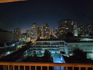 A nighttime cityscape with illuminated buildings and a clear view of a building with multiple floors and windows. - Modern Apartment - 2 Bedrooms, 2 Bathrooms, and Parking (Santiago)