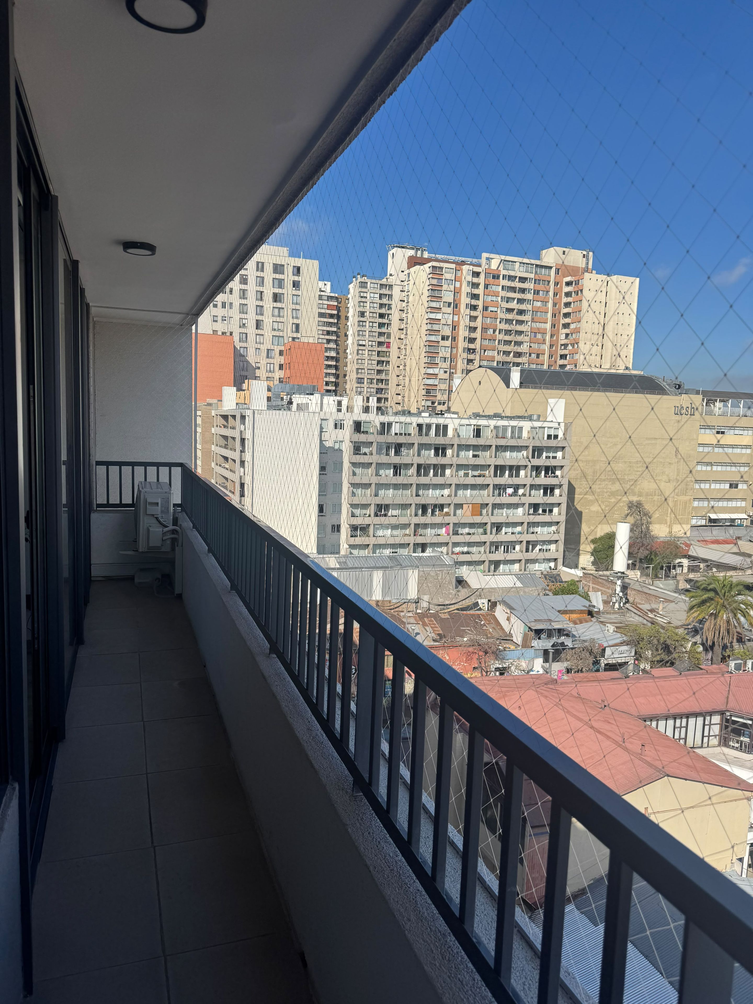 Ein Balkon mit Blick auf hohe Gebäude und einen klaren Himmel.