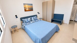 A bedroom with a bed, bedside tables, a wardrobe, and a bench. - Beachfront villa with a garden and private parking on the property. (Avola)