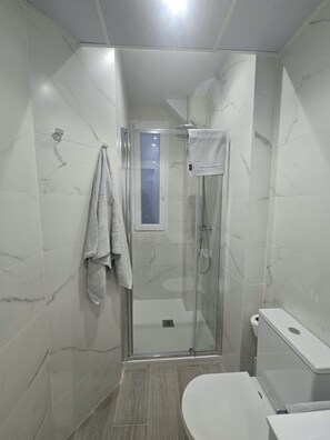 A bathroom with a glass-enclosed shower, a toilet, and a towel rack. - (ALC124) 3 bedroom apartment in Goya (Madrid)