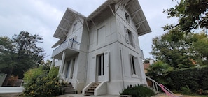 Um edifício de dois andares com varanda e escadaria que leva à entrada.