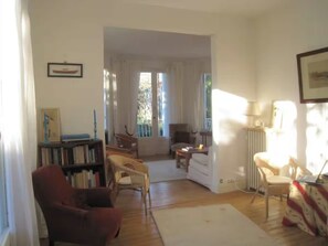 A living room with a fireplace, a bookshelf, and a dining area with a table and chairs. - Large family villa 50m from the beach (Arcachon)