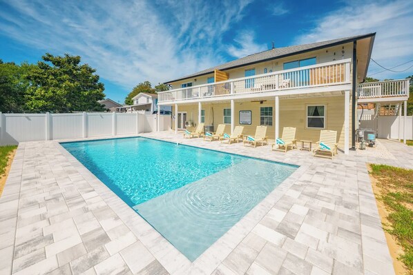 Ein zweistöckiges Haus mit Swimmingpool und überdachter Terrasse.