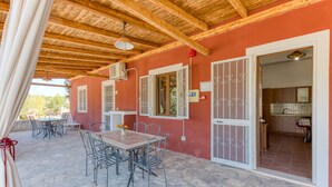 A covered outdoor patio with stone flooring, metal furniture, and a wooden ceiling. - Apartment 'Le Colonie - Bilocale 2' with Private Terrace, Shared Garden and Air Conditioning (Presicce)