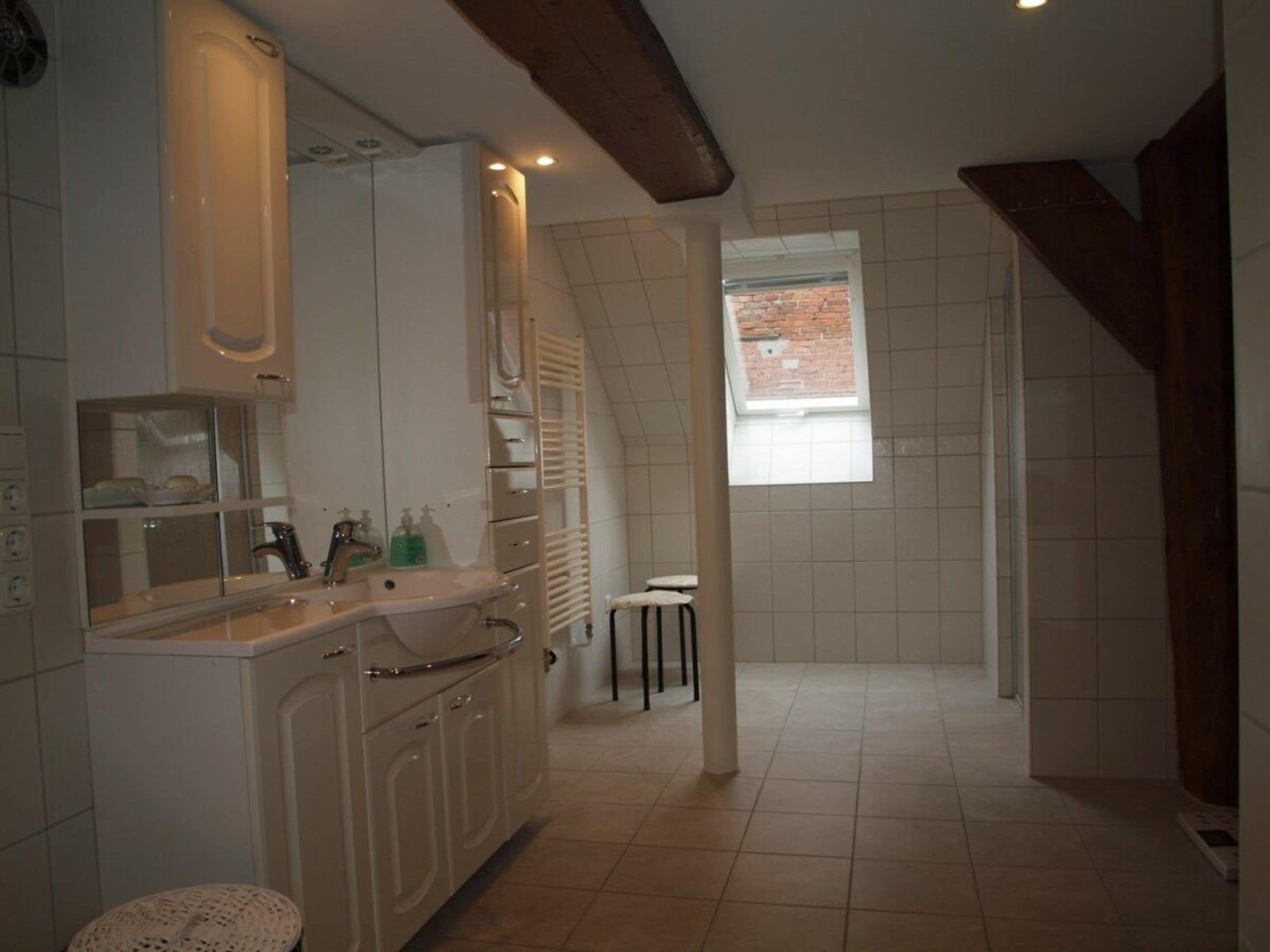 Ein Badezimmer mit Waschbecken, Spiegel und Fenster.