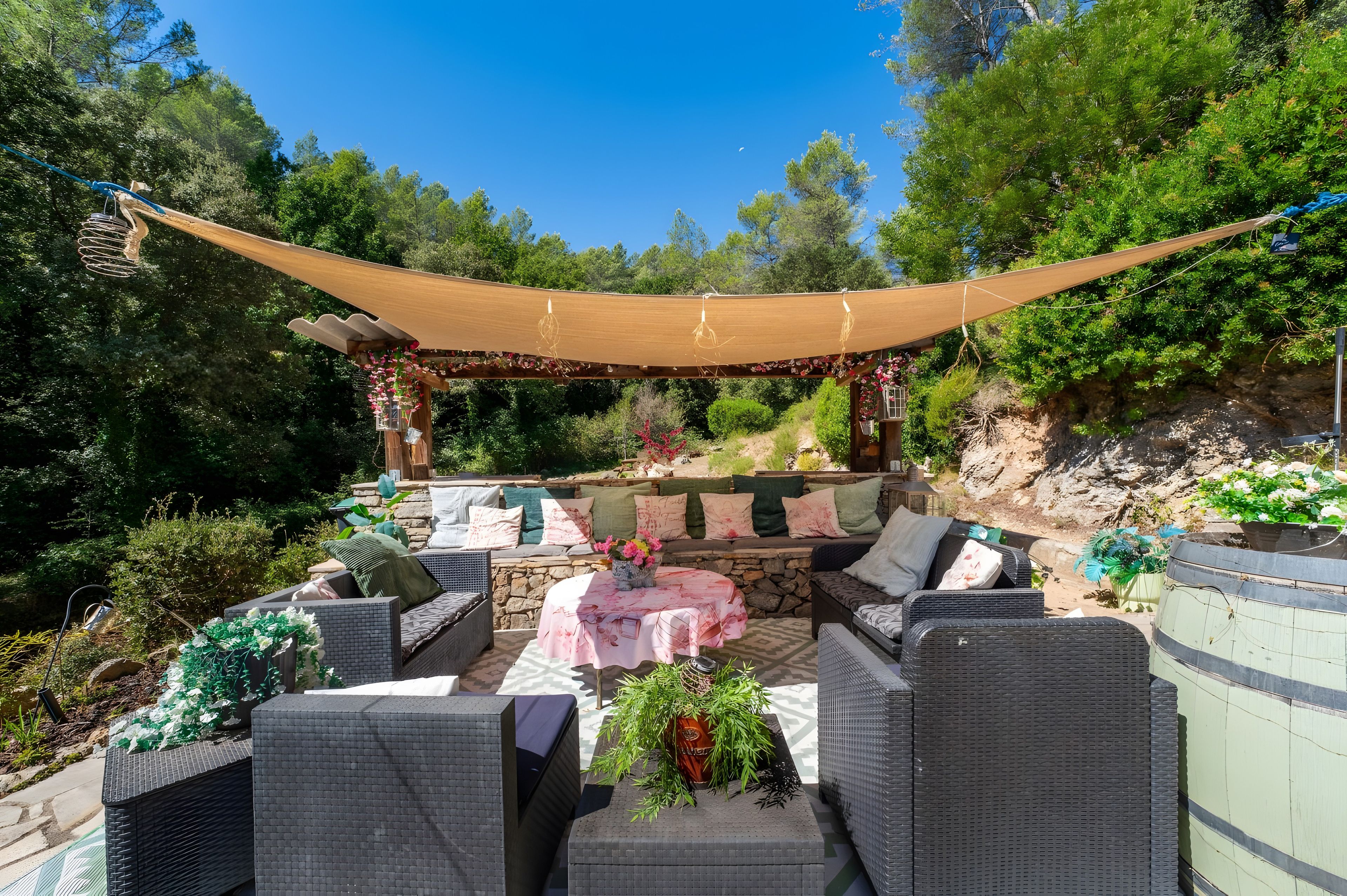 An outdoor patio with wicker furniture, a stone wall, and a pergola.