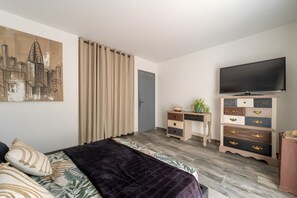 A bedroom with a bed, a television, a dresser, and a door. - Villa 'La Garrigue en Provence' with private pool, air conditioning, 3,000 m² garden, 4 guests (Taradeau)