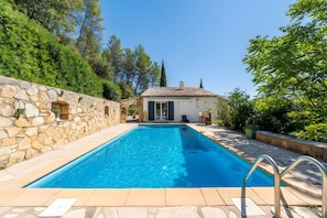 A swimming pool with stone walls and a tiled roof, surrounded by greenery and trees. - Villa 'La Garrigue en Provence' with private pool, air conditioning, 3,000 m² garden, 4 guests (Taradeau)