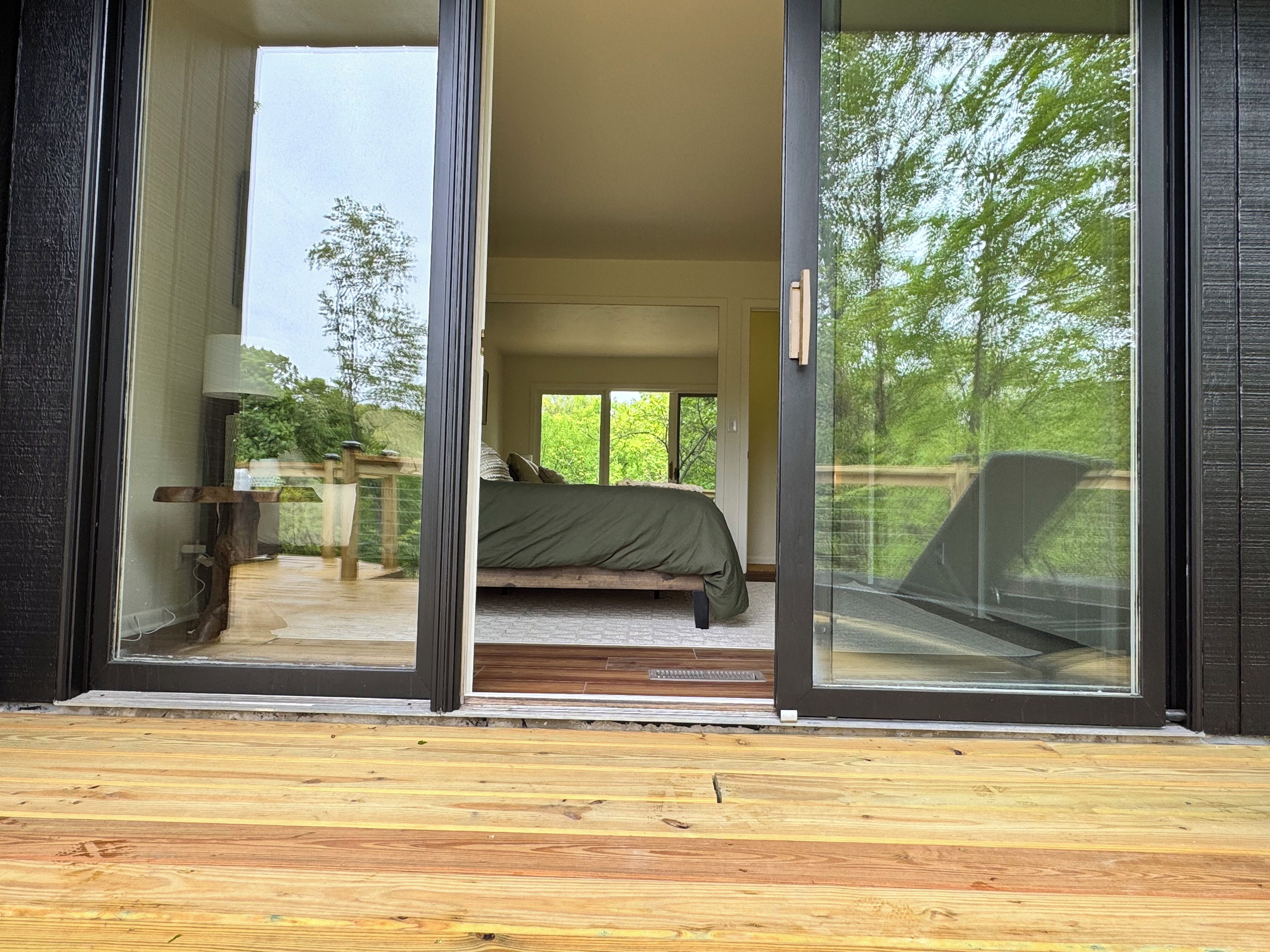 A bedroom with a bed, a window, and a view of greenery outside.
