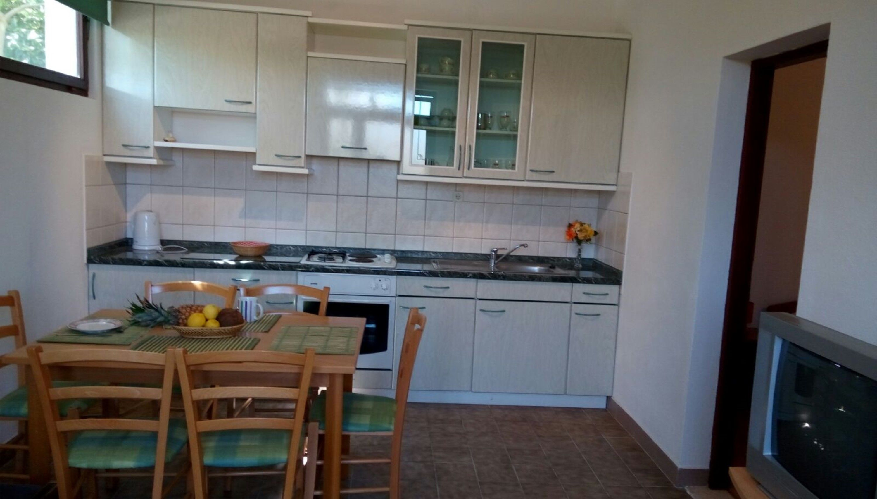 A compact kitchen with white cabinets, a dining table with chairs, and a small countertop.