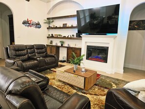 A living room with a fireplace, a flat-screen TV, leather sofas, and a coffee table. - Villa Del Gotti A Luxury Stockyards Experience (Fort Worth)