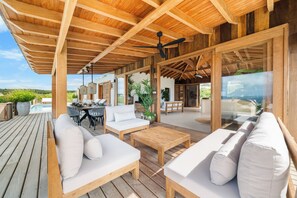 A covered outdoor area with wooden flooring, white sofas, a wooden table, and a ceiling fan. - NEW Oceanview villa, private gym and infinity pool! (Kralendijk)