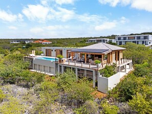 A modern house with a pool, wooden deck, and a covered outdoor area. - NEW Oceanview villa, private gym and infinity pool! (Kralendijk)