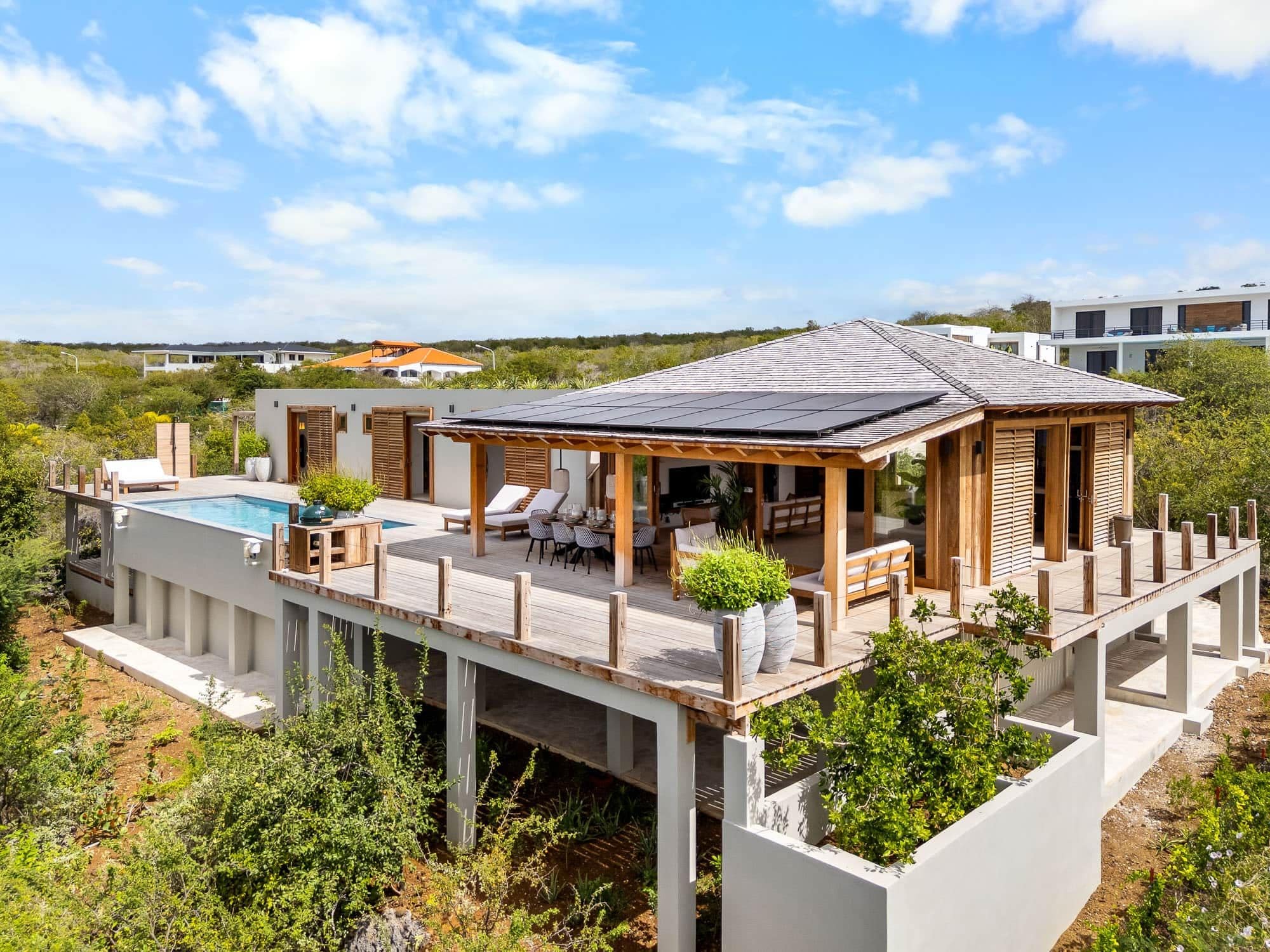 Une maison moderne dotée d’une piscine, d’un espace salon extérieur et d’une terrasse.