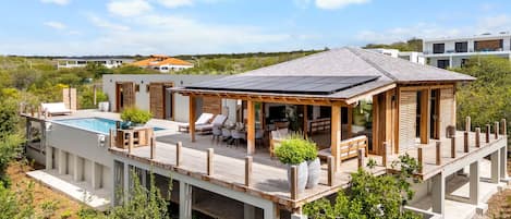 A modern house with a pool, outdoor seating, and a deck.