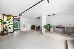 A spacious living area with a large potted plant, a wooden bench, and a modern chair. - NEW Oceanview villa, private gym and infinity pool! (Kralendijk)
