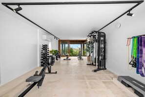 A gym with exercise equipment, a rowing machine, and a wall-mounted resistance band system. - NEW Oceanview villa, private gym and infinity pool! (Kralendijk)