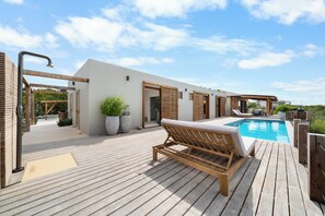 A wooden deck with a pool, lounge chairs, and potted plants. - NEW Oceanview villa, private gym and infinity pool! (Kralendijk)