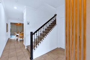 A staircase with a black balustrade leading to a dining area with a table and chairs. - Disney Area Villa w Private Pool & Resort Access (Davenport)