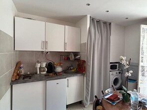 A compact kitchen with white cabinets, a small refrigerator, a coffee maker, and a washing machine. - Ground floor studio with parking near beach (Villers-sur-Mer)