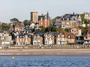 A coastal town with historic buildings, a beach, and a clear sky. - Ground floor studio with parking near beach (Villers-sur-Mer)