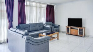 Una sala de estar moderna con un sofá gris, una mesa de centro y un televisor sobre un soporte de madera.