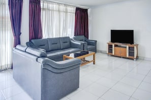 A modern living room with a grey sofa, a coffee table, and a TV on a wooden stand. - Stylish DBL Suite Escape W/ Free Wifi and Parking (Bandar Lampung)