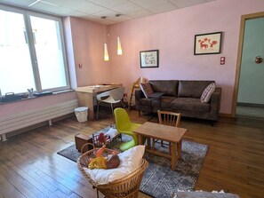 A cozy living room with a sofa, a dining table, and a wicker chair. - Charming house in Blainville-sur-l'Eau - 6 guests (Blainville-sur-l'Eau)