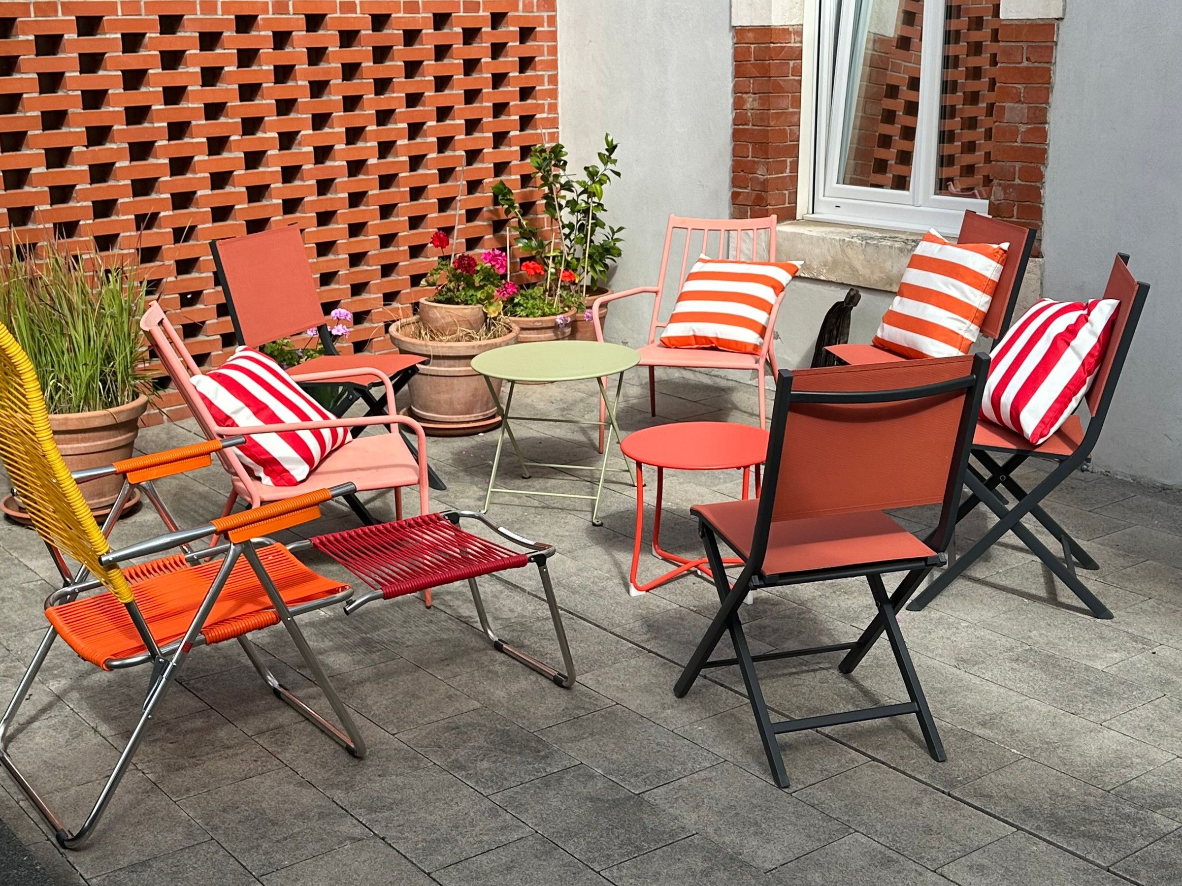 Un patio con mobiliario exterior, incluyendo sillas y una mesa, y plantas en macetas.