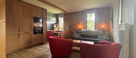 A compact living space with a kitchenette, a sofa, and two armchairs.