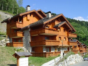 Eine mehrstöckige Holzhütte mit Balkonen vor einer gebirgigen Kulisse.