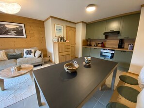 Eine moderne Küche mit einer zentralen Kochinsel, Holzschränken und einem Essbereich mit einer Couch und Couchtisch.