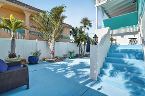 A sunny outdoor patio area with a blue staircase, a white fence, and various potted plants. - Gulfport Getaway with Tropical Outdoor Space (Gulfport)
