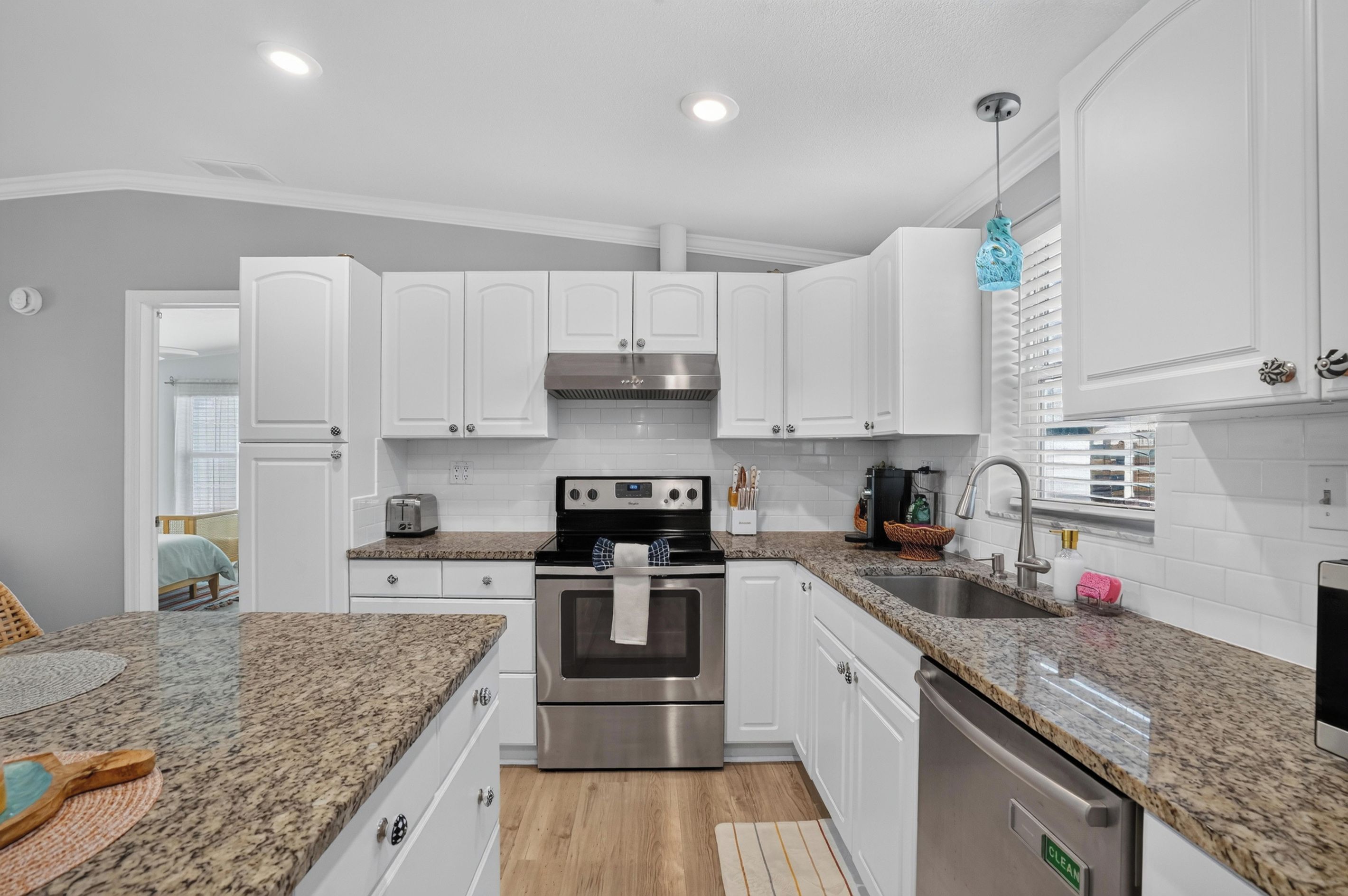 A modern kitchen with white cabinets, a stainless steel oven, and granite countertops.