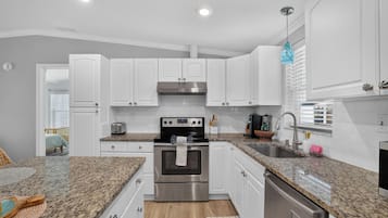 A modern kitchen with white cabinets, a stainless steel oven, and granite countertops.