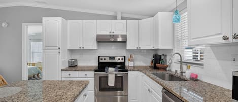 A modern kitchen with white cabinets, a stainless steel oven, and granite countertops.