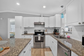 A modern kitchen with white cabinets, a stainless steel oven, and granite countertops. - Gulfport Getaway with Tropical Outdoor Space (Gulfport)
