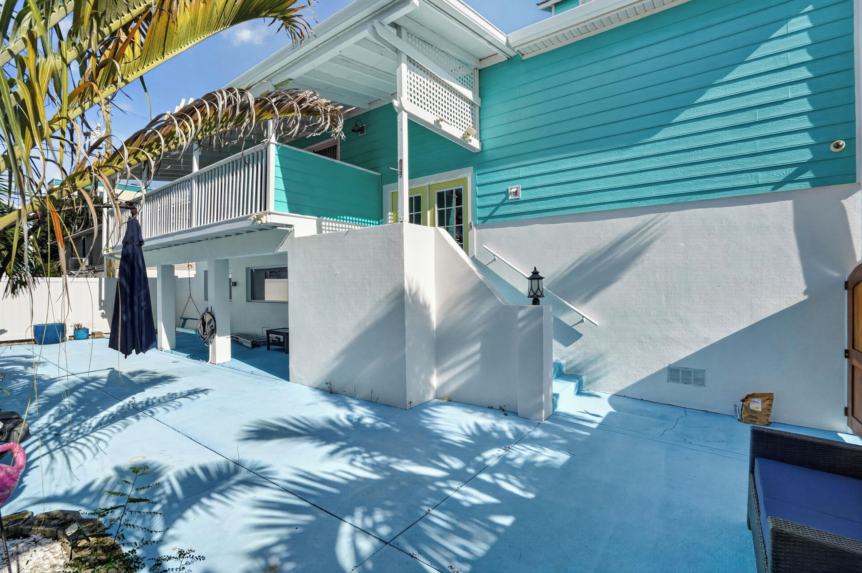 A two-story house with a balcony, a covered porch, and a small outdoor seating area.