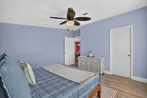 A bedroom with a bed, a ceiling fan, a dresser, and a door. - Gulfport Getaway with Tropical Outdoor Space (Gulfport)