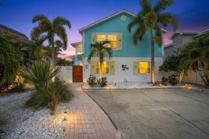 A two-story house with a front porch, palm trees, and a driveway. - Gulfport Getaway with Tropical Outdoor Space (Gulfport)
