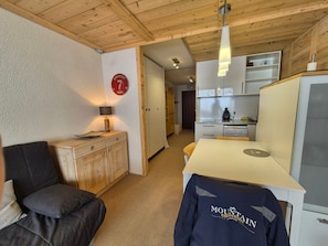 A compact room with a kitchenette, a dining area, and a seating area with a sofa and a table. - Studio cabin near slopes - 4 guests (Tignes)