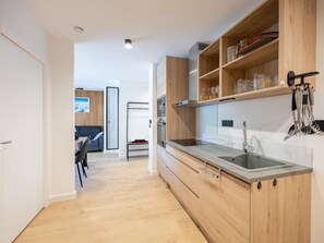 A modern kitchen with wooden cabinets, a stainless steel sink, and a dining area with a table and chairs. - Modern apartment with parking - 4 guests (Saint-Lary-Soulan)