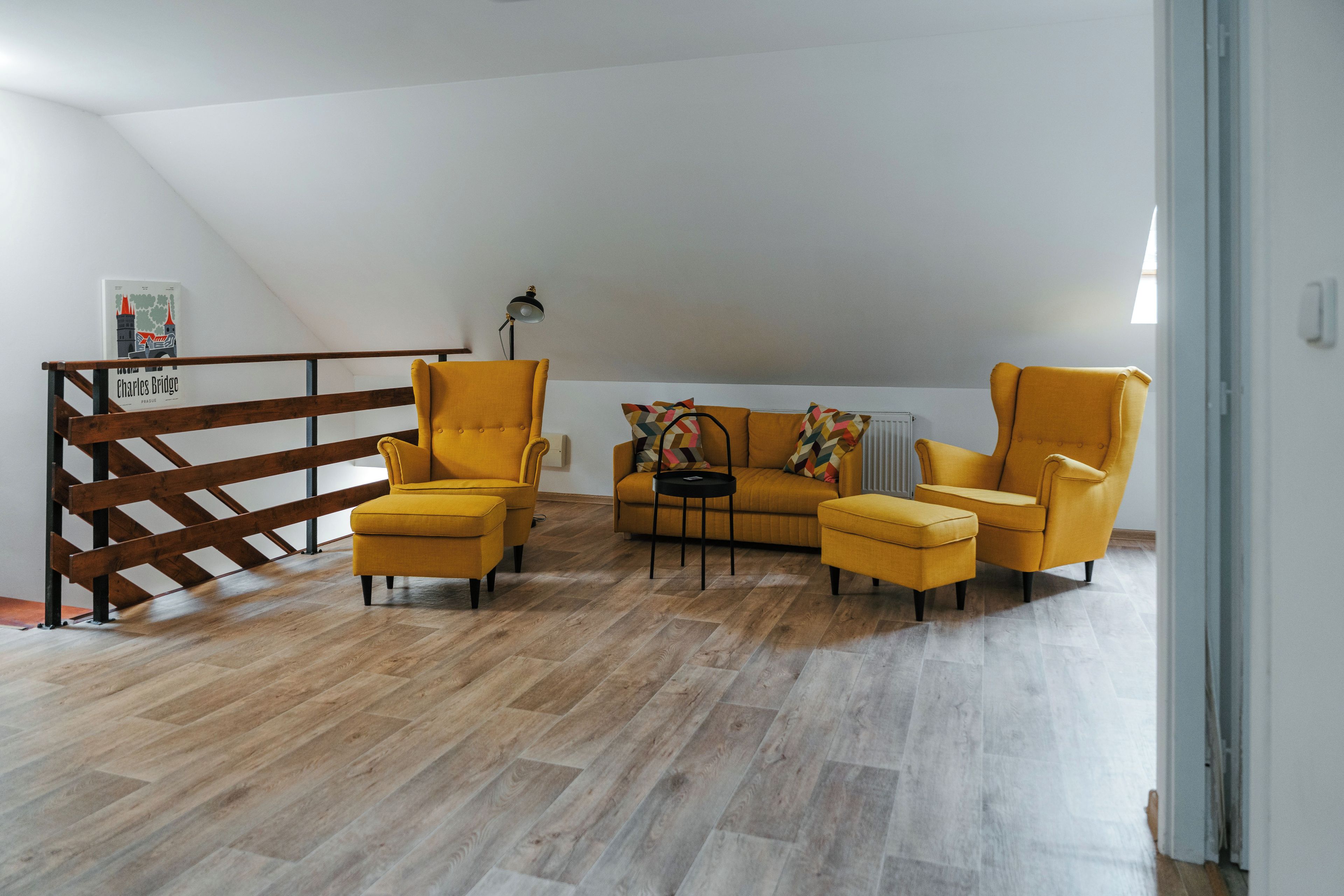 A room with a wooden floor, a sofa set, a coffee table, and a lamp.
