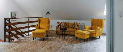 A room with a wooden floor, a sofa set, a coffee table, and a lamp.