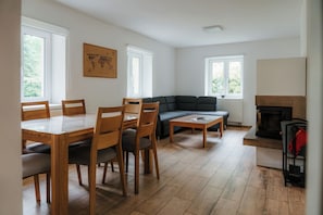 A living room with a dining table, chairs, a sofa, and a fireplace.