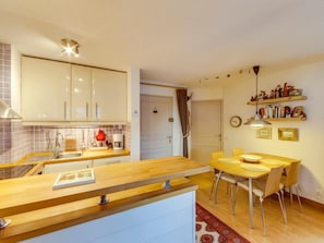 Eine moderne Küche mit weißen Schränken, einer Holzausziehtheke und einem Essbereich mit gelbem Tisch und Stühlen.