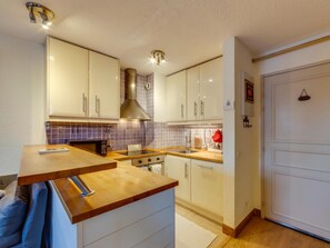Eine moderne Küche mit weißen Schränken, einer Holz Arbeitsplatte und einer Edelstahl-Dunstabzugshaube.