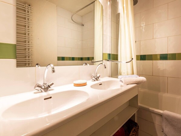 Een badkamer met twee wastafels, een spiegel en een douche.