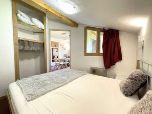 A bedroom with a bed, a wardrobe, a mirror, and a window with curtains. - Pleasant apartment, pets allowed - 6 guests (Valfréjus)
